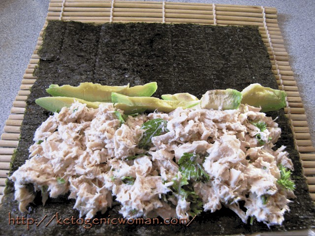 tuna and avocado on a nori sheet laid out on a sushi mat