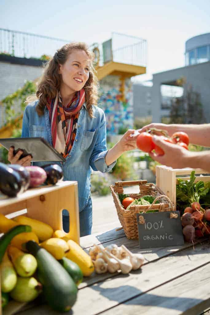 Woman shopping for cheap produce in season at farmers market