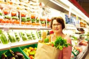 woman in grocery store holding bag of groceries