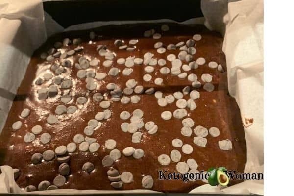 keto brownie batter shown in pan with parchment paper sling