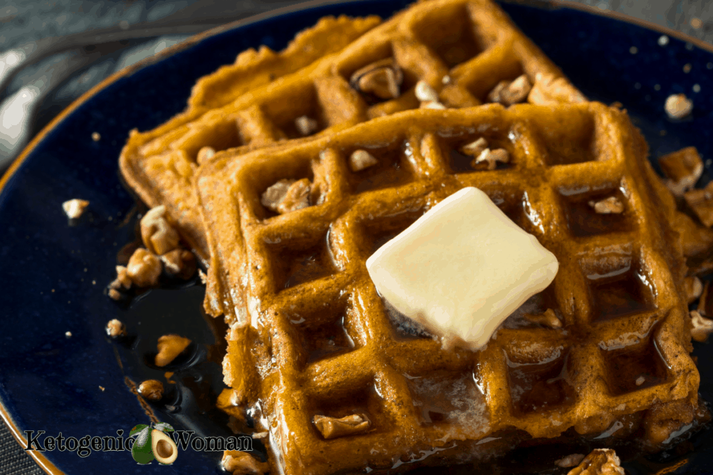 Pumpkin spice waffles with butter and nuts on blue plate