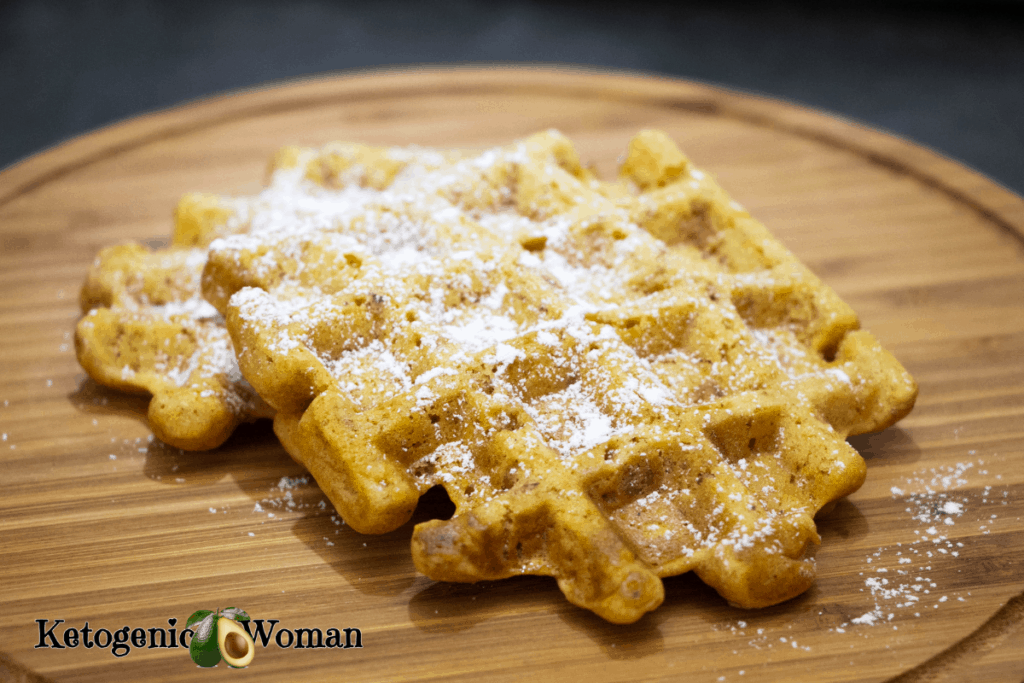 Keto pumpkin spice waffles with powdered sugar on wooden board